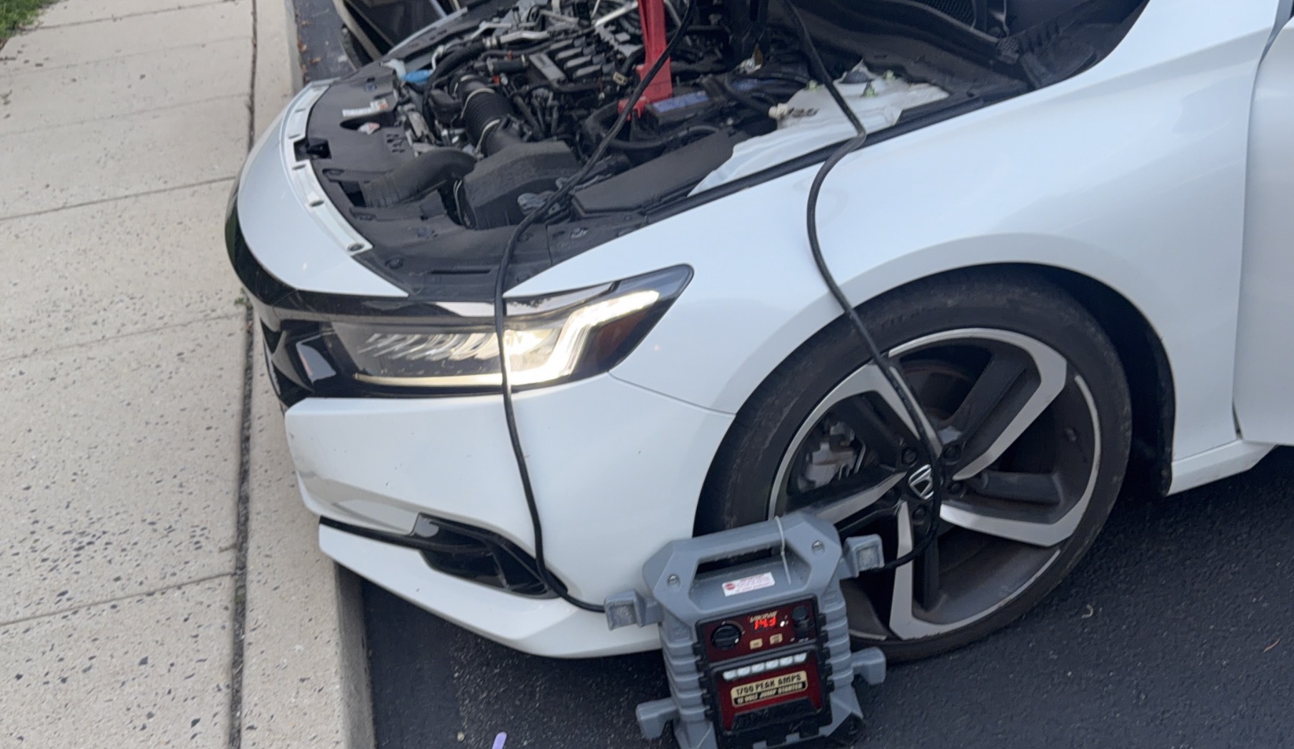 Portable jump starter connected to a Honda Accord for a roadside jump start
